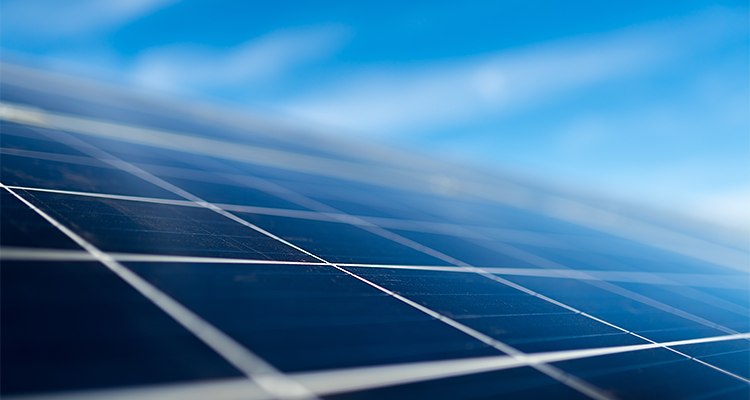 A set of solar panels are sat beneath a blue sky.