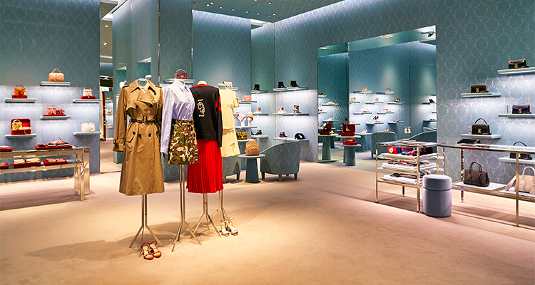 Mannequins dressed in luxury clothing in an empty store.