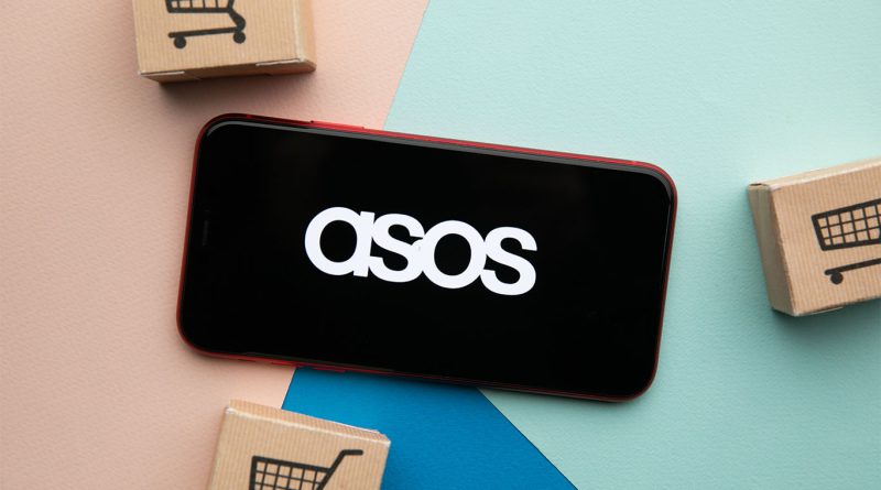 Image of the ASOS logo on a phone screen next to wooden boxes with shopping cart icons printed on them to support ASOS India article