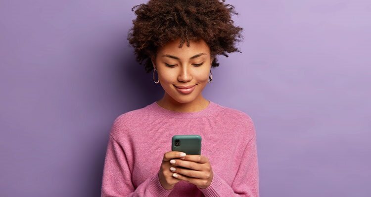Lady checking mobile phone in front of purple background