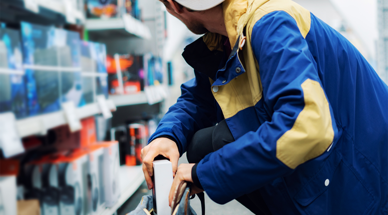 Close-up of a man in a store putting items into a bag to support retail theft article