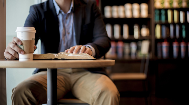 A Starbucks customer holding a branded coffee cup in a café setting, highlighting the Starbucks Rewards loyalty program experience