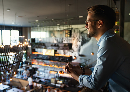 Happy businessman, restaurant owner proudly looking at crowded restaurant