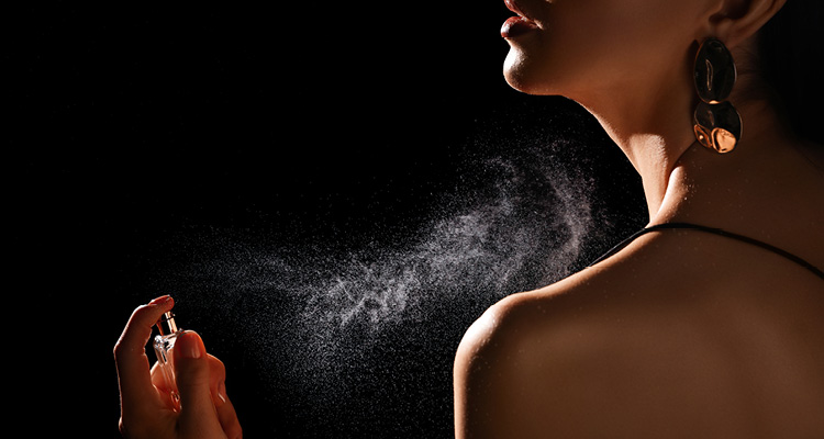 a close-up of a person spraying perfume onto their neck
