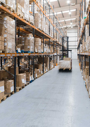 a logistics warehouse interior featuring tall metal racking systems filled with palletized goods.