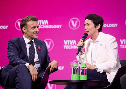 French President Emmanuel Macron is shown on stage alongside Rachel Delacour, the CEO and co-founder of the carbon-accounting platform Sweep
