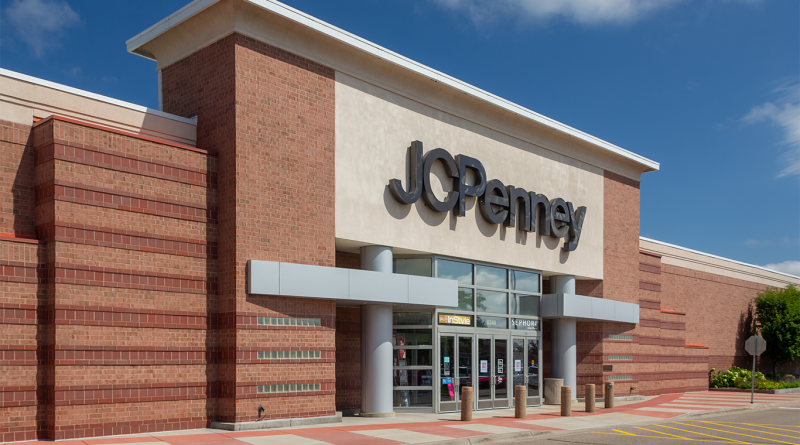 Exterior of a JCPenney department store with its logo above the main entrance under a blue sky.