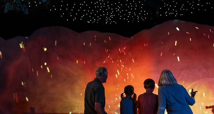 visitors experiencing an immersive campfire projection display inside the Theodore Roosevelt Presidential Library in Medora, North Dakota