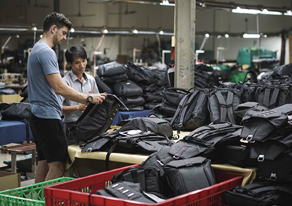 a person inspecting a black backpack on a factory floor